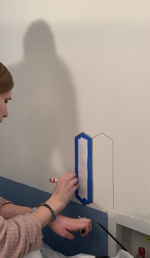 a woman is painting a wall with white paint and blue trim on the edge of it