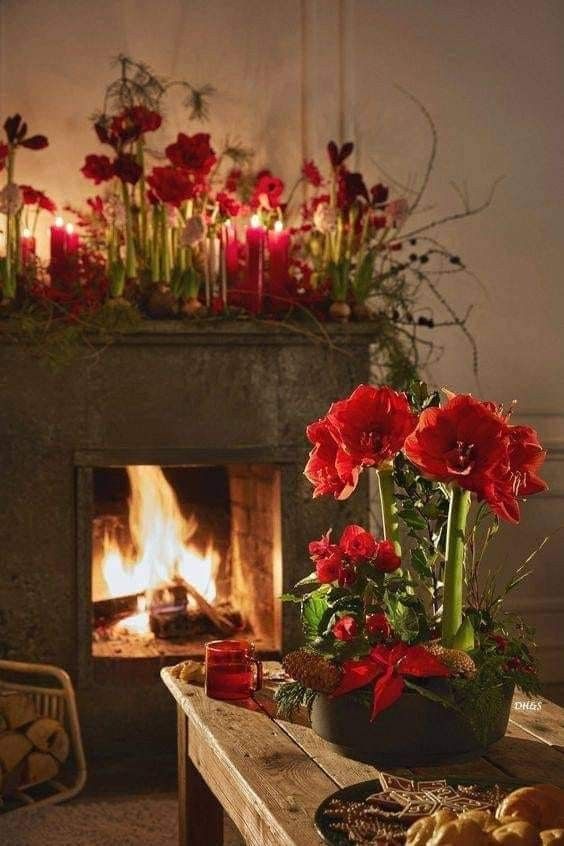 a fireplace with flowers and candles on it in front of a fire place filled with food