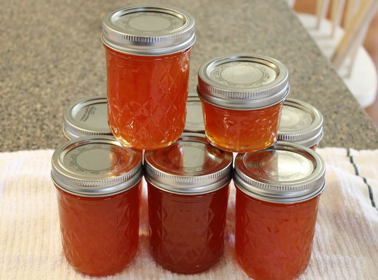 six jars filled with red liquid sitting on top of a wooden table next to a white towel