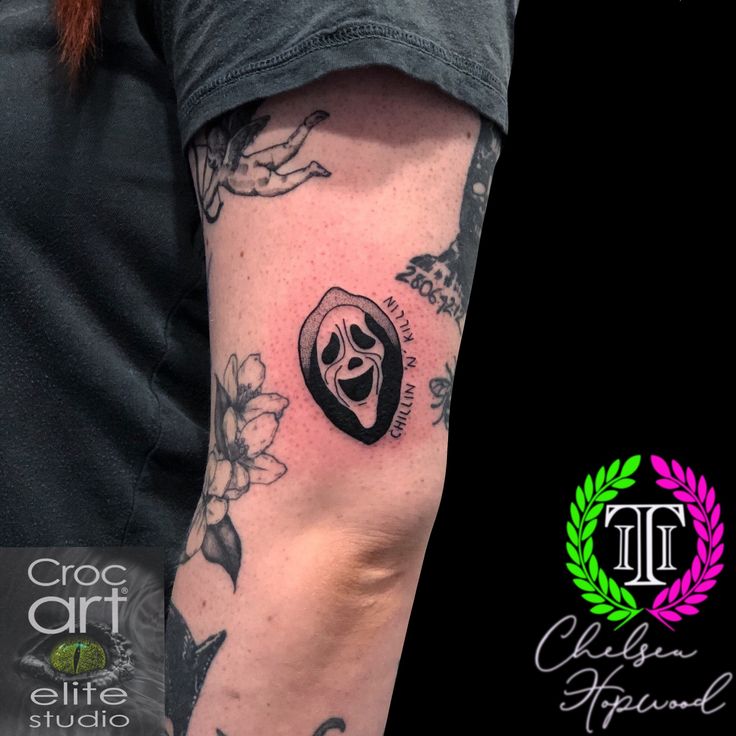 a woman's arm with a skull and flower tattoo on the left side of her arm