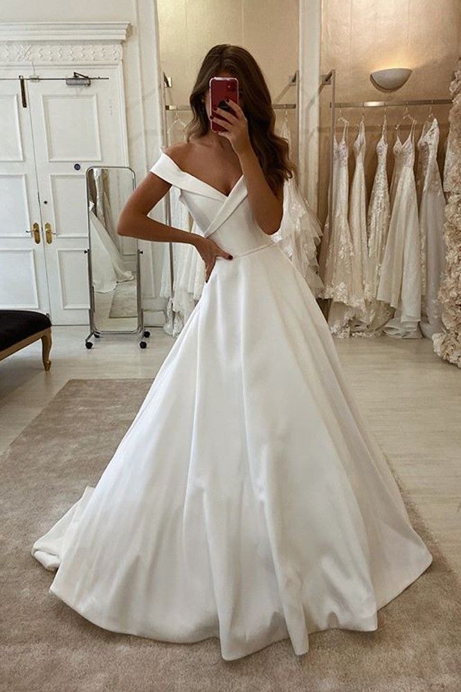 a woman in a white wedding dress taking a selfie with her cell phone while looking into the mirror