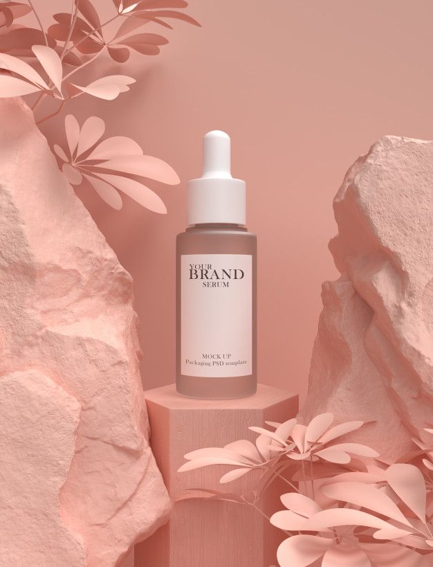 a bottle of brand skin oil sitting on top of a pink surface next to rocks and flowers