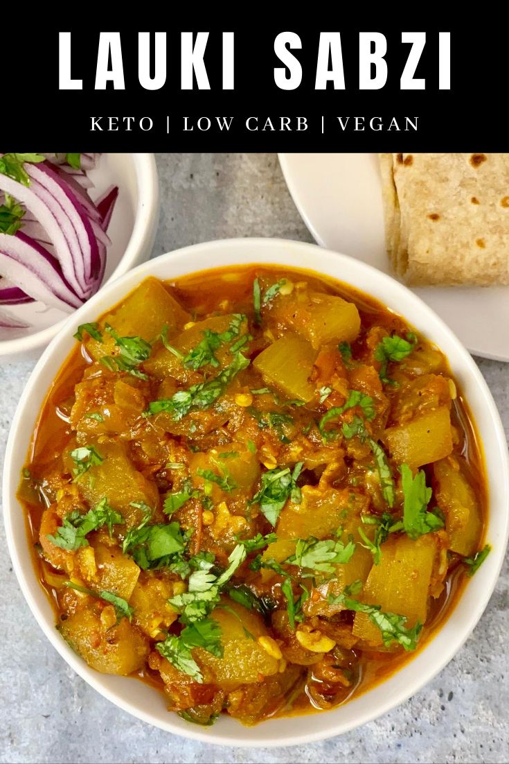 a white bowl filled with curry next to some bread and vegetables on a table top