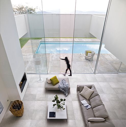 a living room filled with furniture next to a swimming pool in the middle of an open floor plan