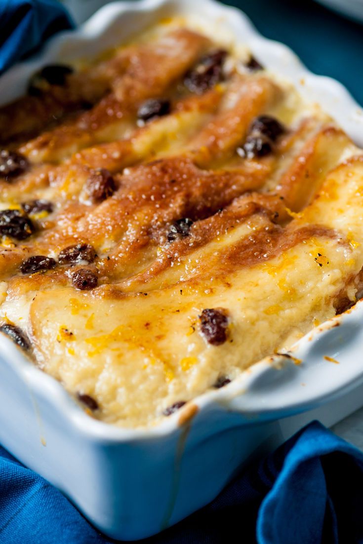 a casserole dish with cheese and raisins in it on a blue cloth