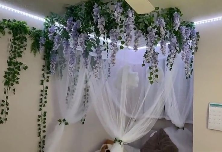 the bedroom is decorated with purple flowers and greenery hanging from the ceiling over the bed