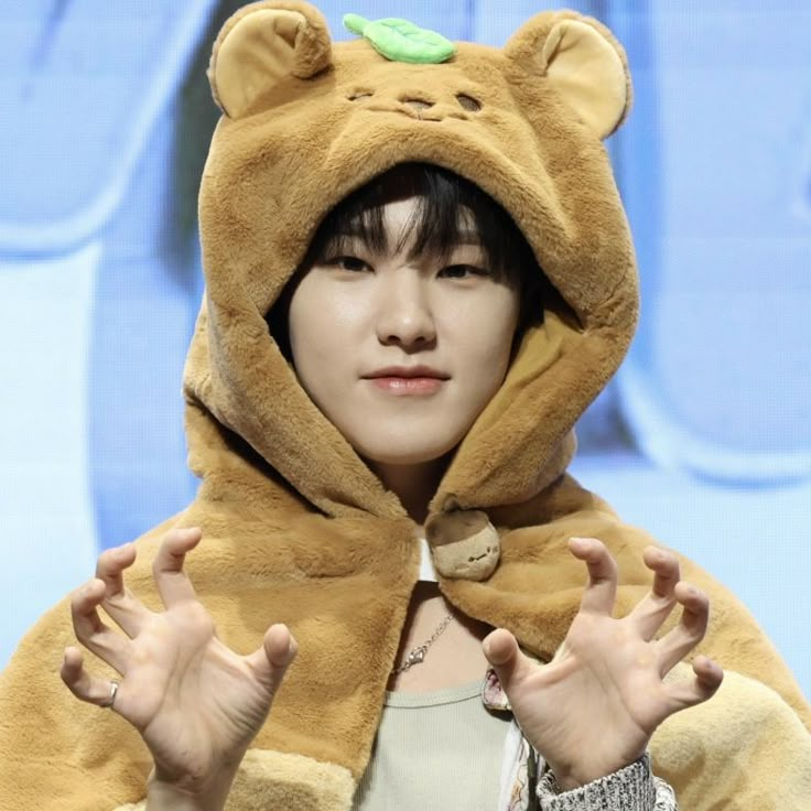 a woman wearing a bear costume on stage with her hands in front of her face