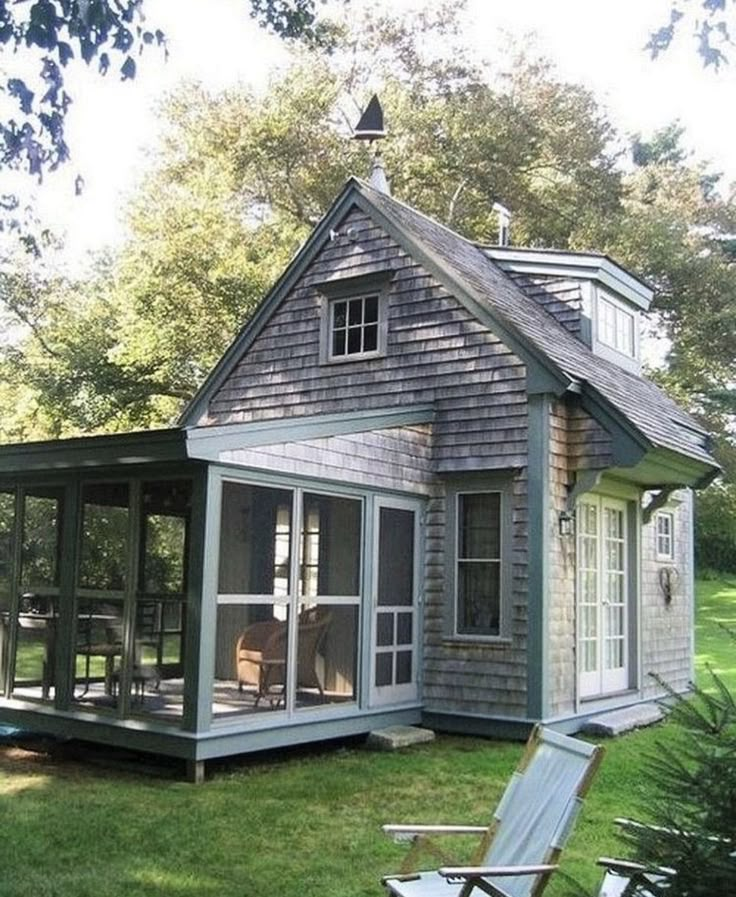 a small gray house sitting on top of a lush green field