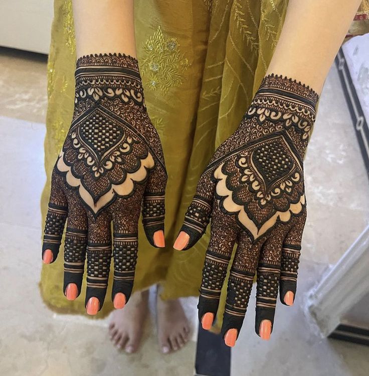 a woman's hands with hennap on it and orange nails in front of her