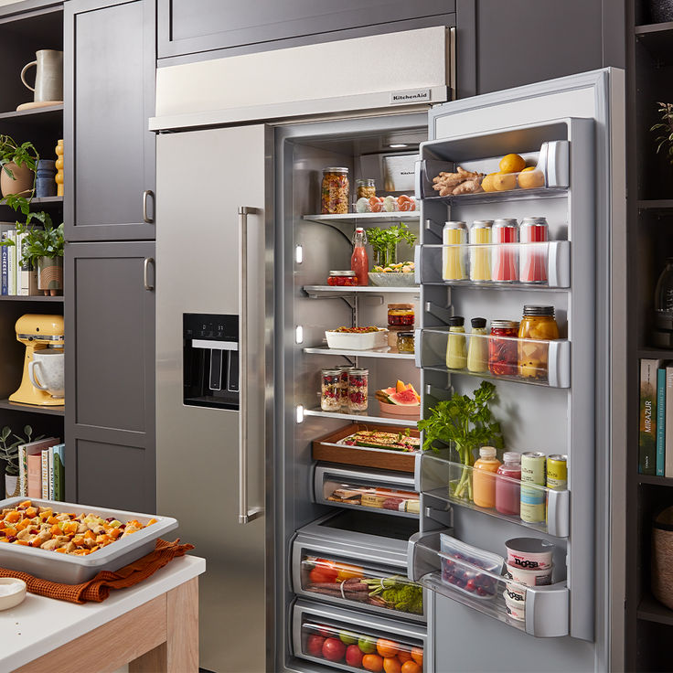 a stainless steel refrigerator with its door open and food in the freezer compartment,