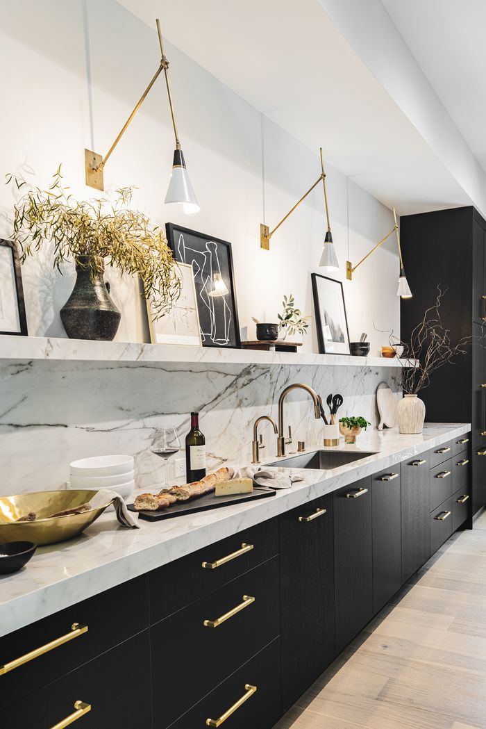 a kitchen with marble counter tops and gold pulls on the cabinets, along with brass accents