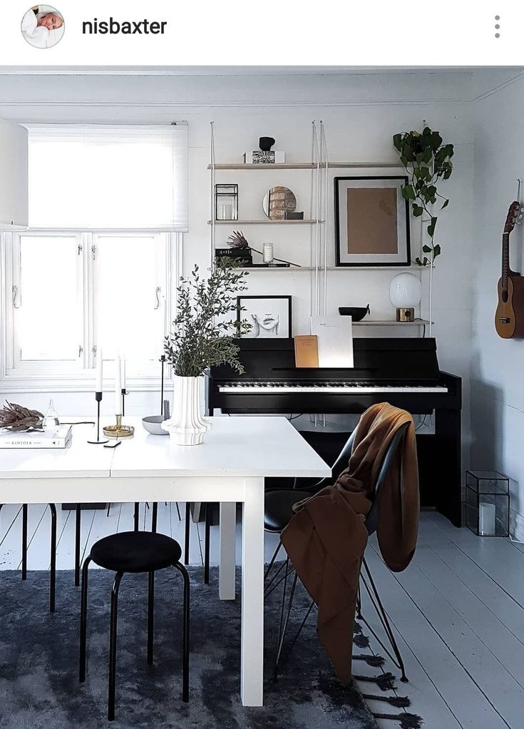 a room with a table, piano and other items on the wall above it in front of a window