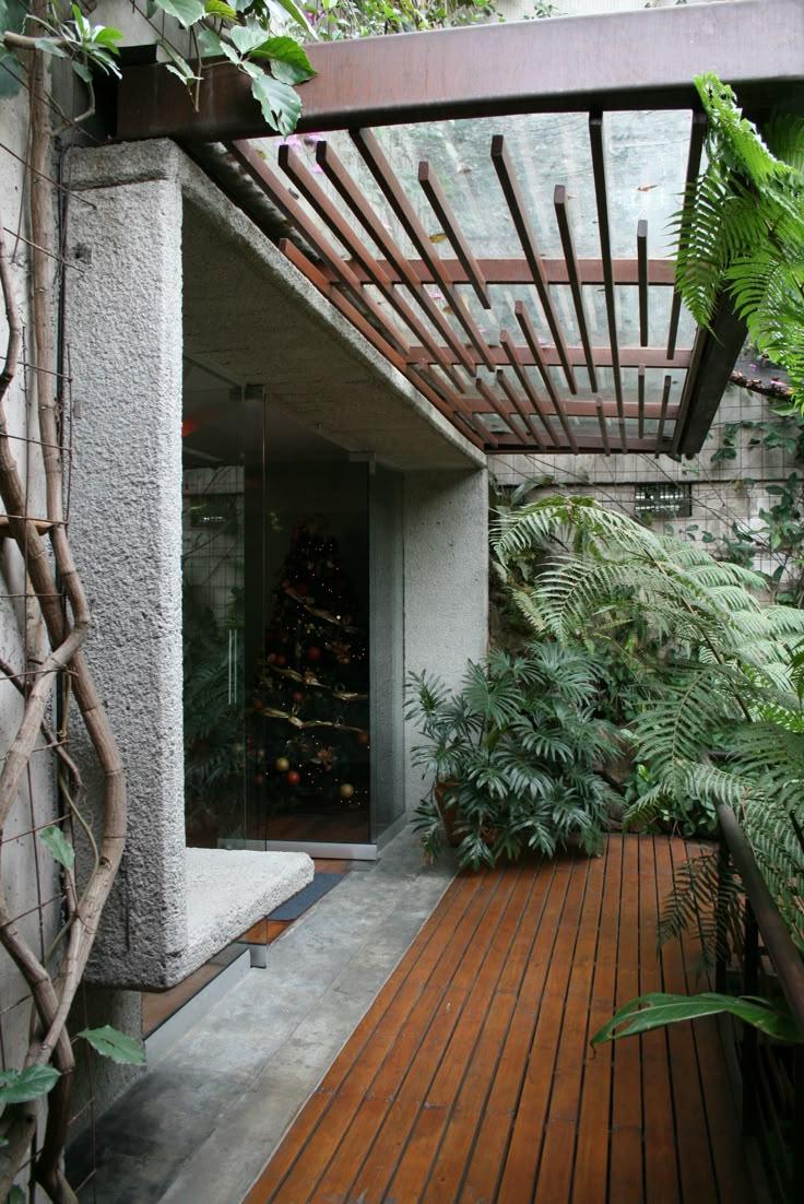 a wooden deck in front of a building with trees and plants on the outside wall