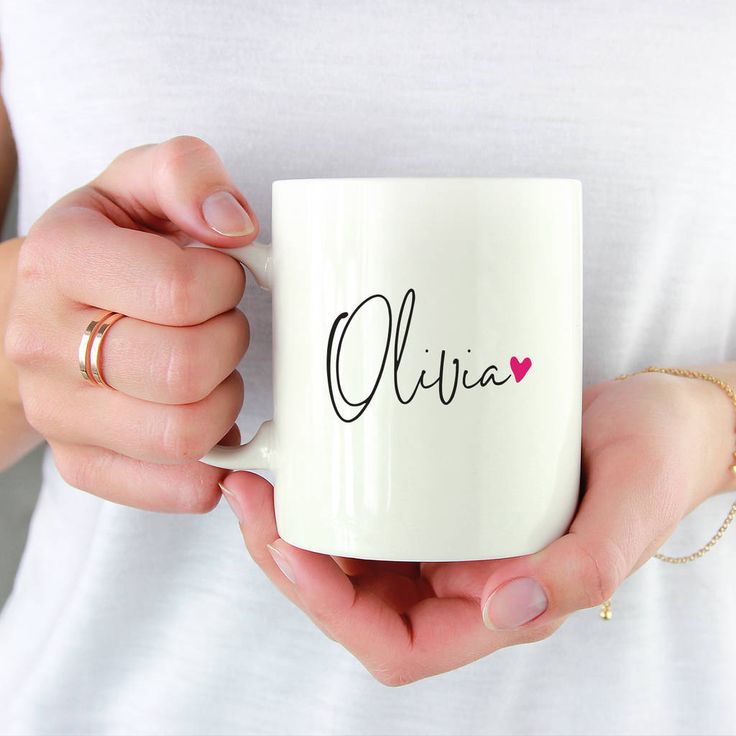 a woman holding a white coffee mug with the word mia on it