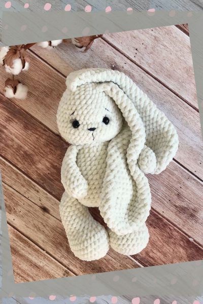 a white knitted stuffed animal sitting on top of a wooden floor