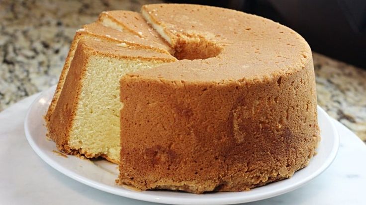 a bundt cake on a white plate with a slice taken out of it and sitting on a marble counter top