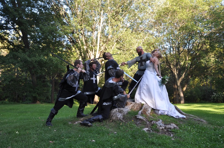 a group of people dressed up in medieval costumes posing for a photo on the grass