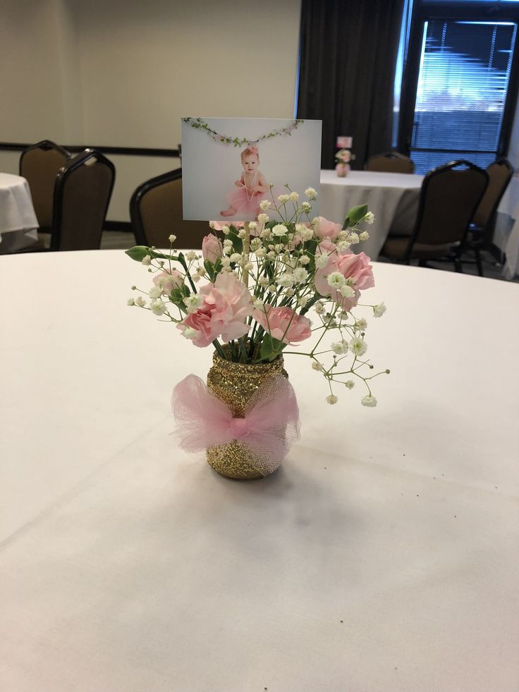 a vase filled with pink and white flowers on top of a round table in a room