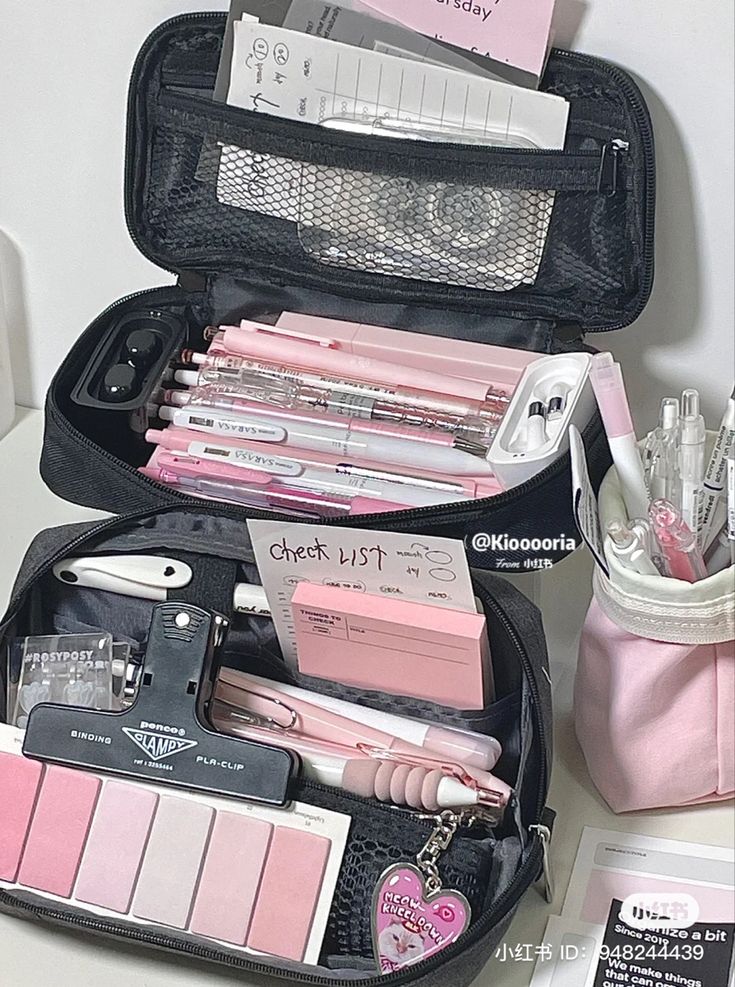 an open black suitcase filled with lots of pink items on top of a white table