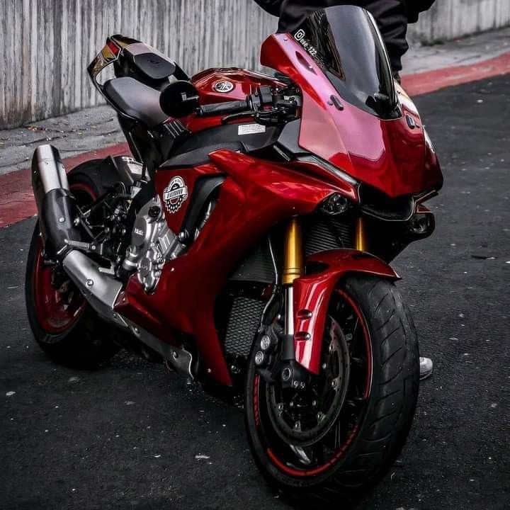 a red motorcycle parked on the street next to a person in black pants and sneakers