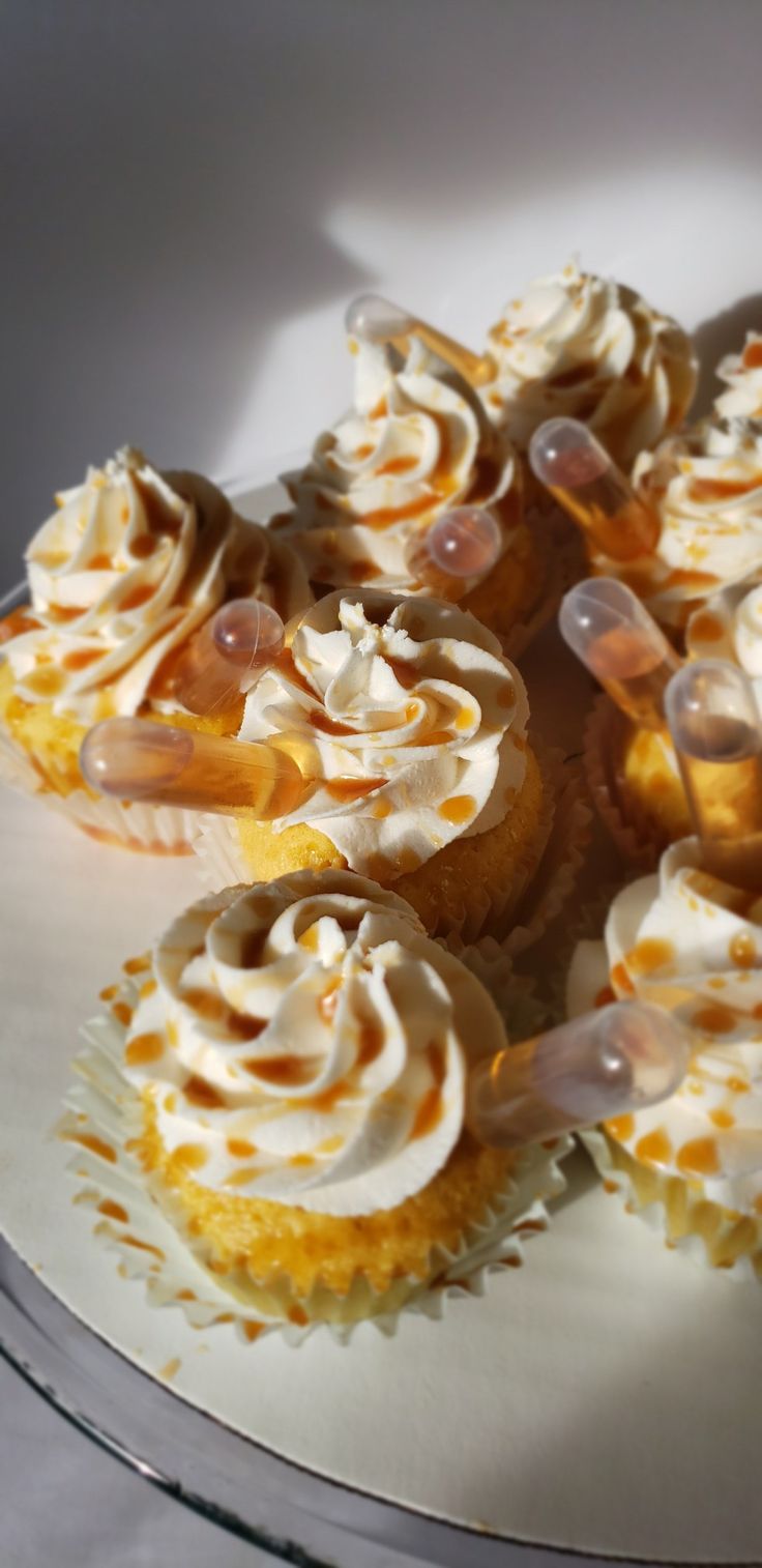 cupcakes with white frosting and orange sprinkles on a plate