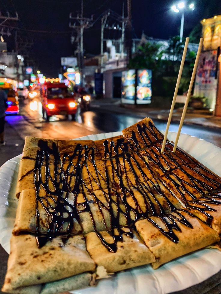 a plate with some kind of food on it and people walking down the street in the background