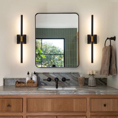 a bathroom vanity with two mirrors and lights on the wall, along with a sink