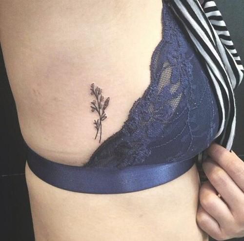 a woman's stomach with a small flower tattoo on her side ribcage