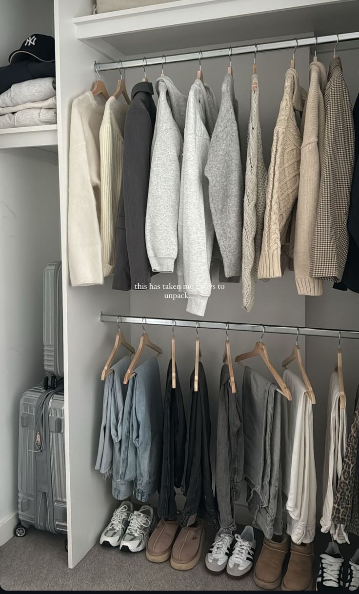 an organized closet with clothes and shoes hanging on the rail, next to a suitcase