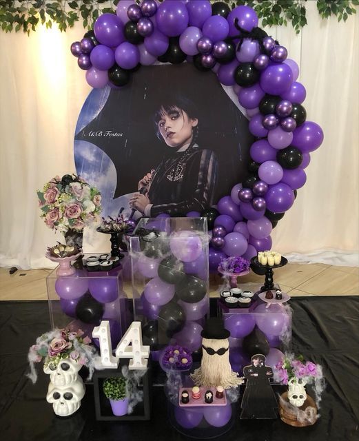 purple and black balloons are on display in front of a large photo frame with skulls