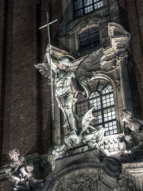 an artistic photo of a statue in front of a building with a cross on it