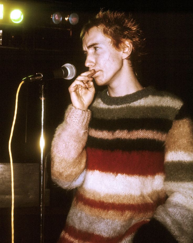 a young man standing in front of a microphone and holding his hand to his mouth