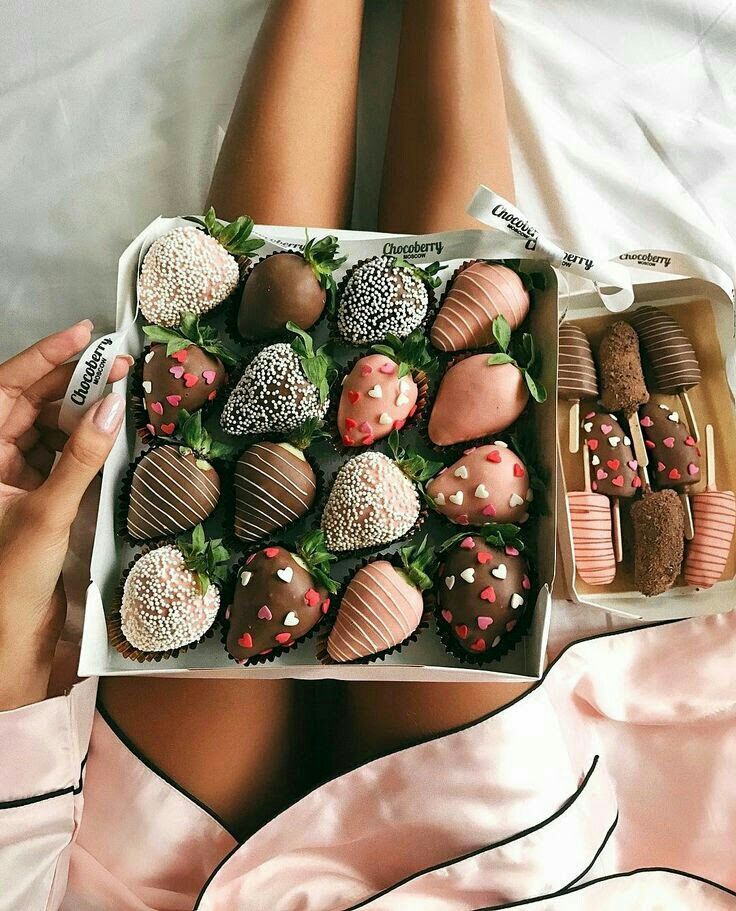 a box full of chocolate covered strawberries on top of a woman's stomach