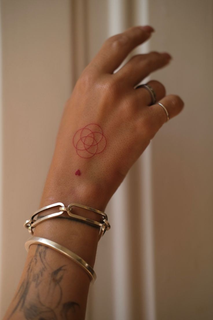 a woman's arm with a rose tattoo on the wrist and two gold bracelets