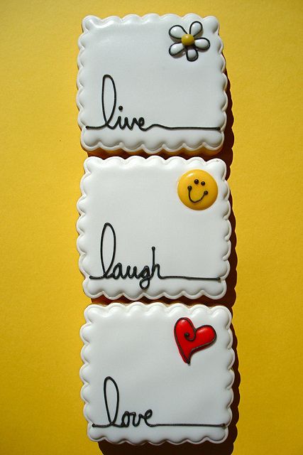 three decorated cookies with the words live laugh love and smiley faces on them, sitting in front of a yellow background