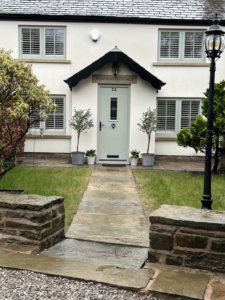 a white house with two windows and a light pole in front of it that has steps leading up to the door