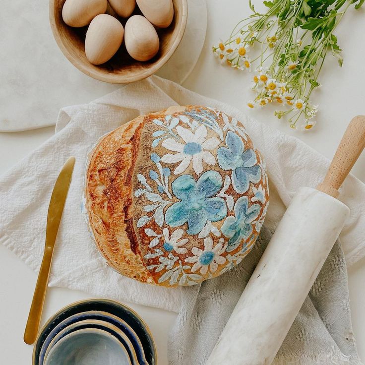 an image of bread with flowers on it and eggs in the bowl next to it