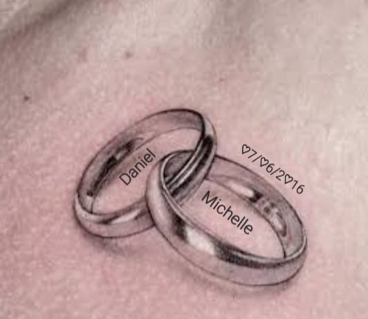 two wedding rings with names on the side of their stomach, one is engraved in black ink