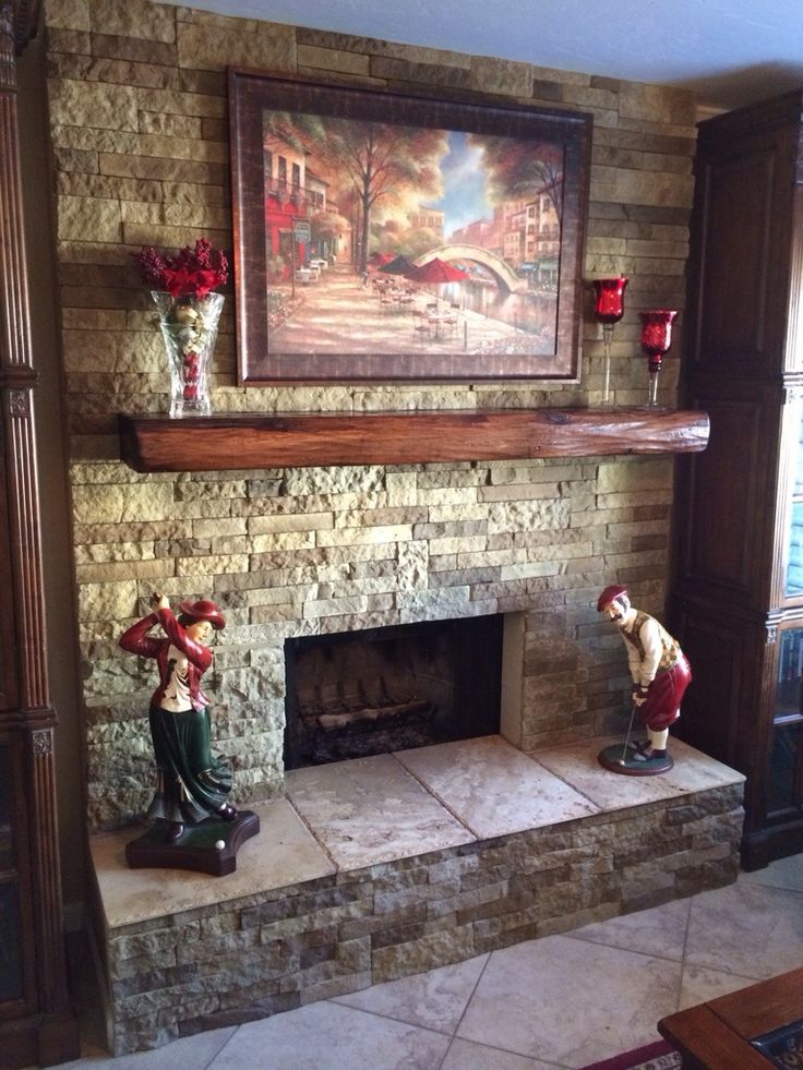 a living room with a fire place and painting on the wall above it's mantle