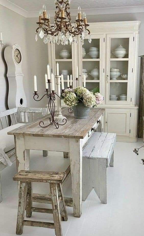 a dining room table with two stools in front of it and a chandelier hanging from the ceiling