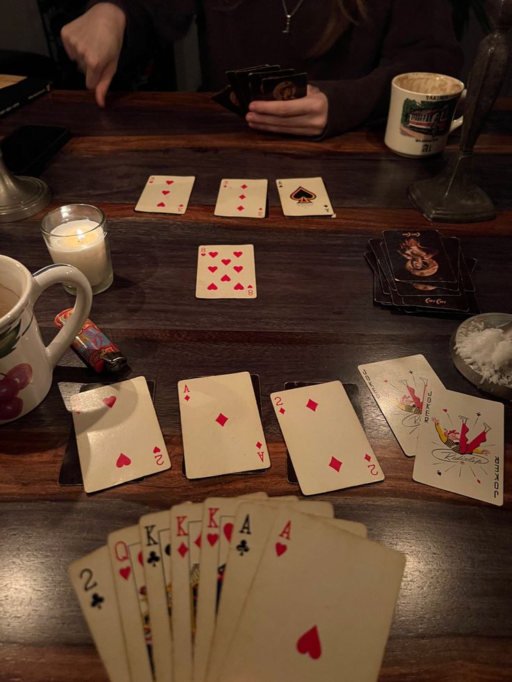 playing cards and cups on a wooden table