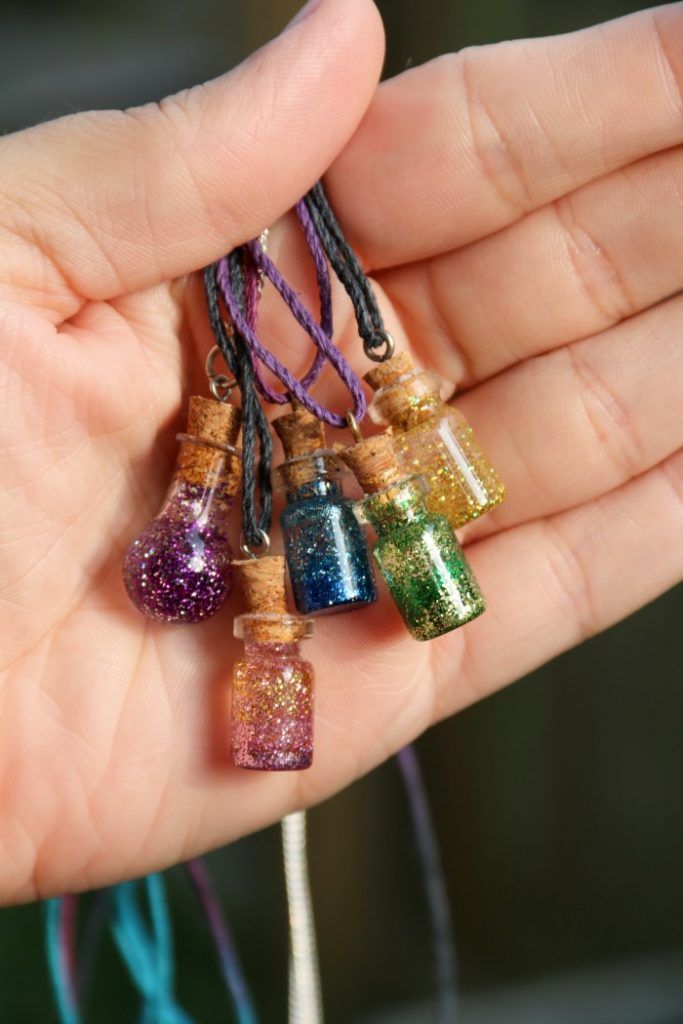 a person is holding some small bottles in their hand and there are several beads hanging from them