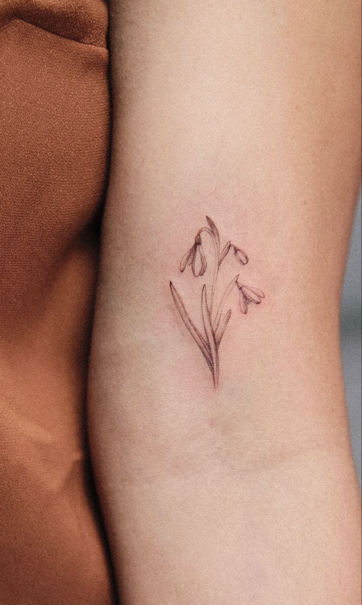 a small flower tattoo on the side of a woman's right arm and thigh