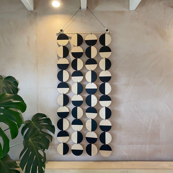 a large black and white art piece hanging on the wall next to a potted plant