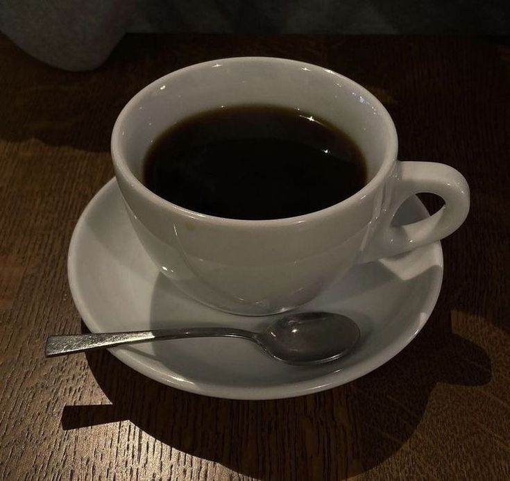 there is a cup of coffee on the saucer with a spoon next to it