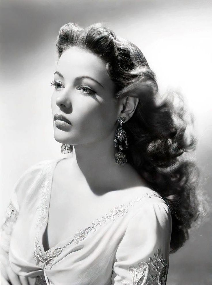 a black and white photo of a woman with long hair in an elegant dress looking off to the side