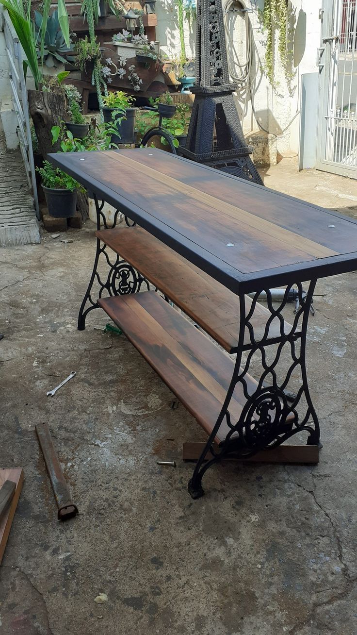 a wooden bench sitting on top of a cement floor next to a metal frame structure