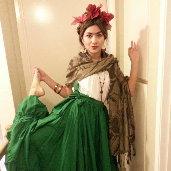 a woman in a green skirt and scarf posing for the camera with her hand on her hip