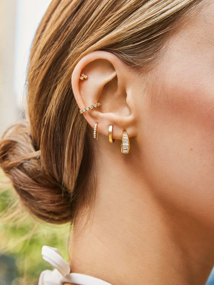 a woman wearing two gold ear clips