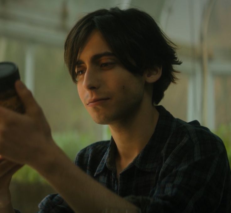 a man holding a cup in his right hand and looking at the screen on his left